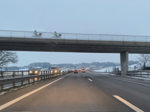 Eine Autobahnbrücke mit zwei identischen Velofahrern